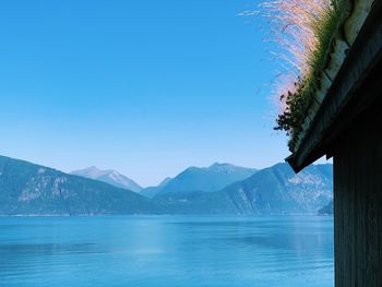 Scenic view of lake and mountains against clear blue sky