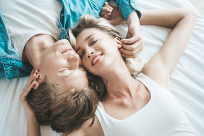 High angle view of couple embracing while lying on bed