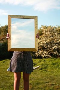 Rear view of woman standing on field against sky