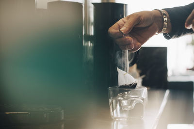 Cropped image of businesswoman making tea in drinking glass at office