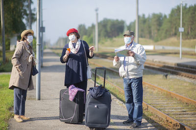 Elderly seniors people with face masks waiting for train before traveling during a covid-19 pandemic