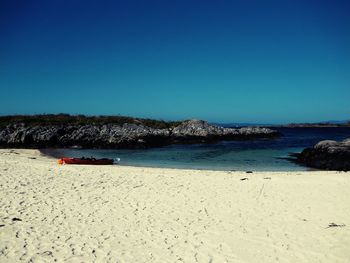 Scenic view of beach against clear blue sky