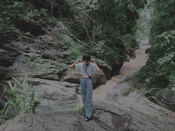 Rear view of man standing on rock in forest