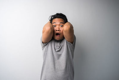 Portrait of young man standing against white background