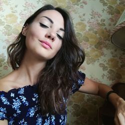 Close-up of beautiful young woman standing against wall