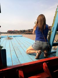 Rear view of woman photographing at beach