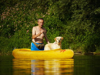 Man rowing in canoe with dog