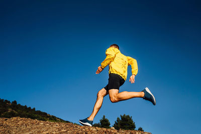 Full length of man running against clear blue sky