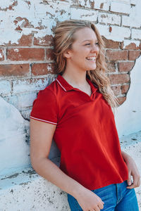 Smiling young woman standing against brick wall