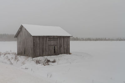 House on snow covered field against sky