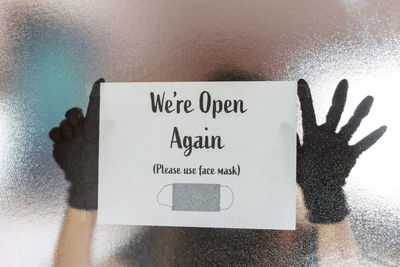 Close-up of hand holding text on paper against wall