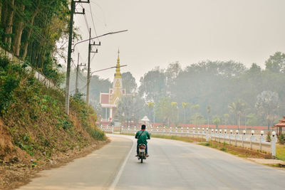 Rear view of man riding motorcycle on road in city