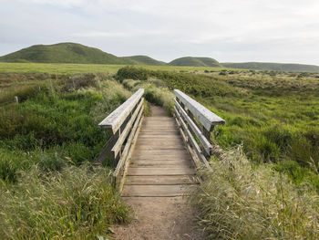 Boardwalk on field against sky