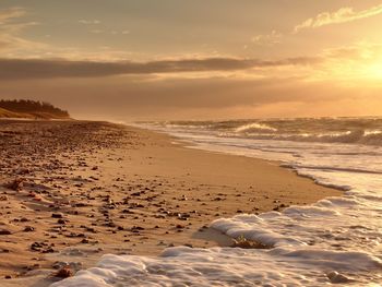 Stones and water trails in beach sand. traces on beach at smooth sea, coastline in summer evening