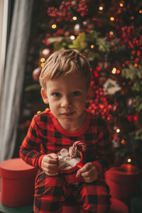 Portrait of cute girl holding christmas tree at night