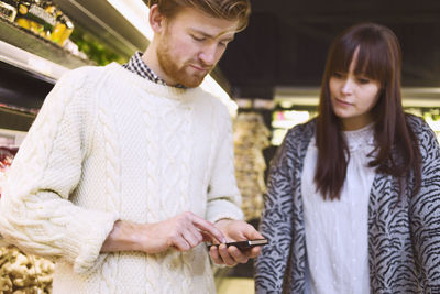 Young couple using smart phone in supermarket