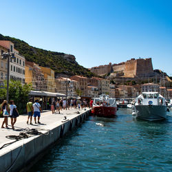 People at waterfront against clear blue sky