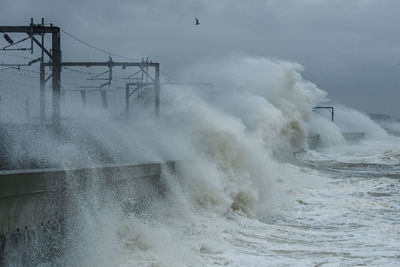 Waves splashing on shore against sky