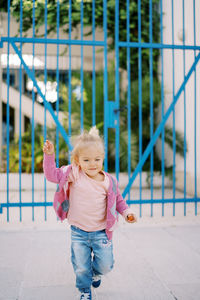 Portrait of cute girl standing by chainlink fence
