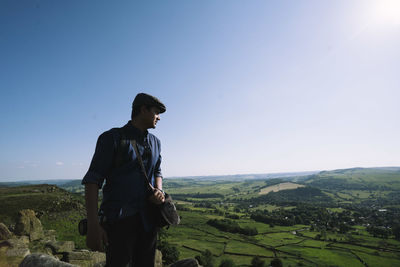 Young man looking at view while hiking on mountain against sky