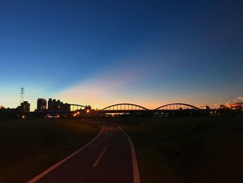 Road by bridge against sky during sunset