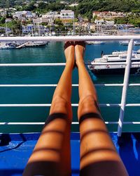 Low section of woman relaxing on ship in sea