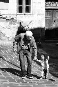 Full length of grandfather wearing coronavirus mask and grandson outdoors