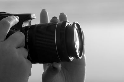 Midsection of man holding camera against sky