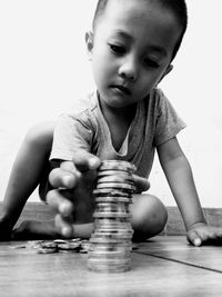 Cute boy stacking coins on floor