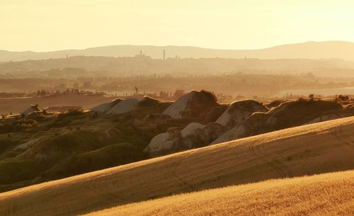Scenic view  of tuscan clay hills  and mountains in golden light . siena towers in the background .