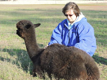 Woman with alpaca on grassy field