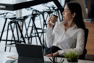 Woman using mobile phone while sitting on table