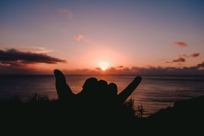 Silhouette person by sea against sky during sunset