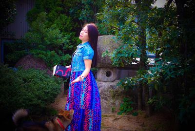 Woman standing by tree trunk