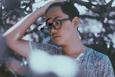 Portrait of young man with eyeglasses on tree