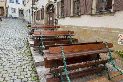 Empty bench by street against buildings in city