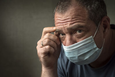 Close-up portrait of man wearing mask against gray background