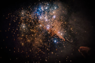 Cropped hand holding sparkler at night