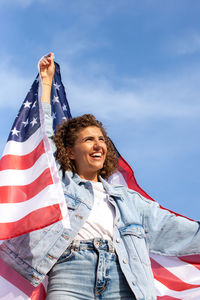 Slim beautiful woman holding usa flag celebrating independance us day. portrait of curly  woman