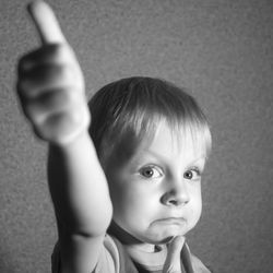 Portrait of cute boy gesturing against wall