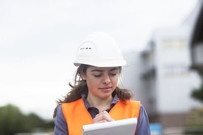 Female worker with clipboard taking notes on industrial site