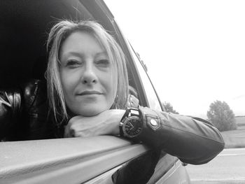 Close-up portrait of young woman sitting on car