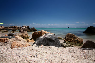 Rocks on beach against blue sky