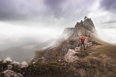 Man standing on rock against sky