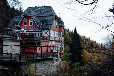 Low angle view of house and trees by lake against sky