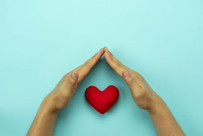 Close-up of hand holding heart shape against white background