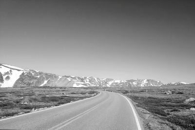 Road leading towards mountain against clear sky