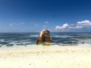 Woman by rock formation at beach on sunny day