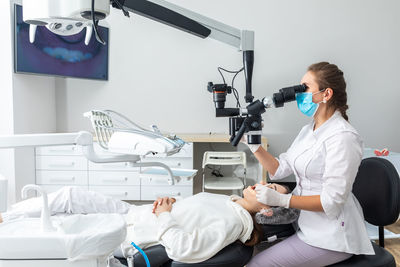 Side view of woman using mobile phone while sitting at clinic