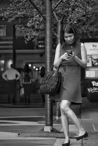 Full length of young woman using mobile phone